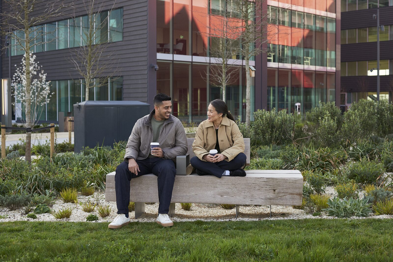 Two people talking on a bench outside the lab buildings